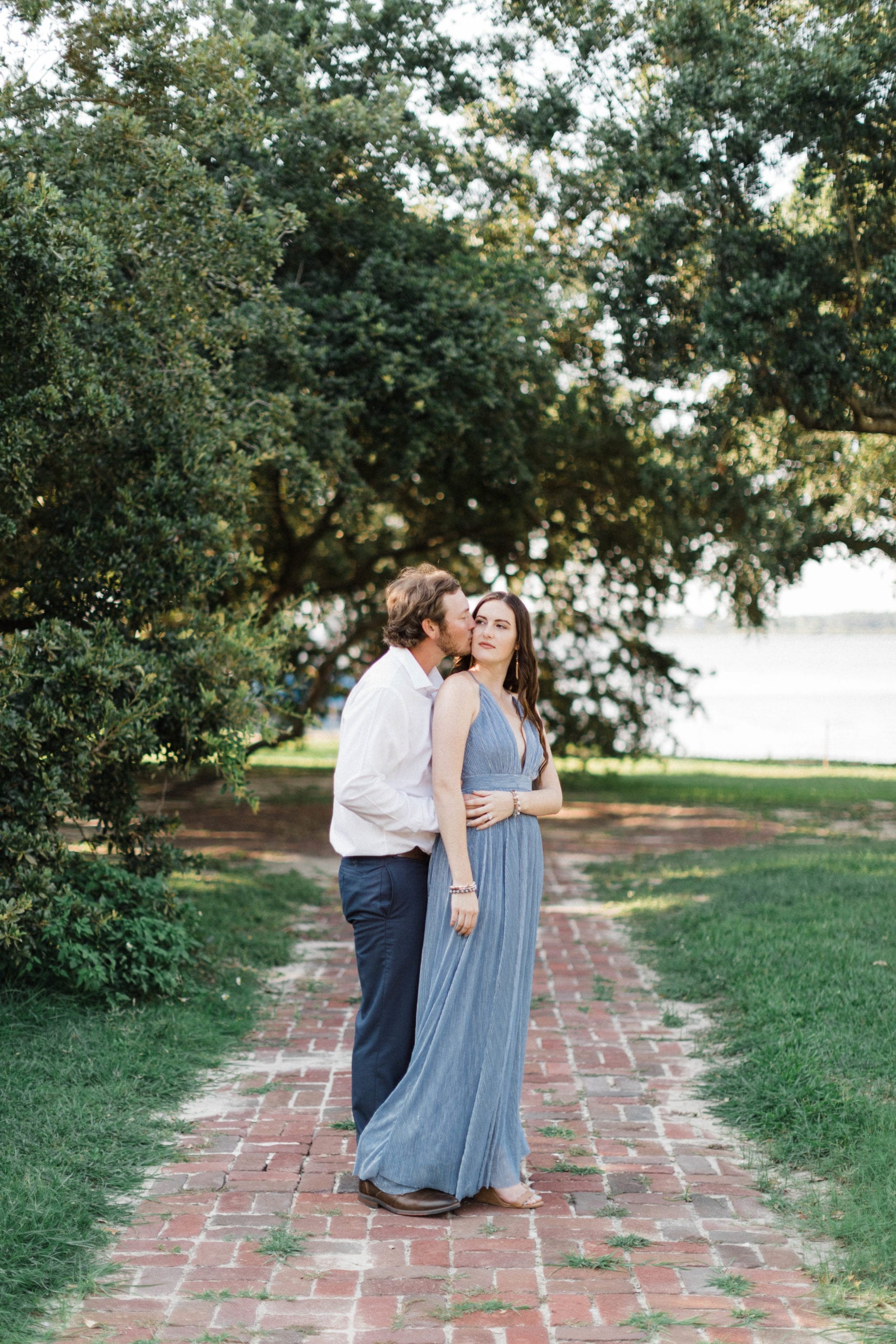 engaged couple embrace on brick walkway at Biloxi's Old Brick House