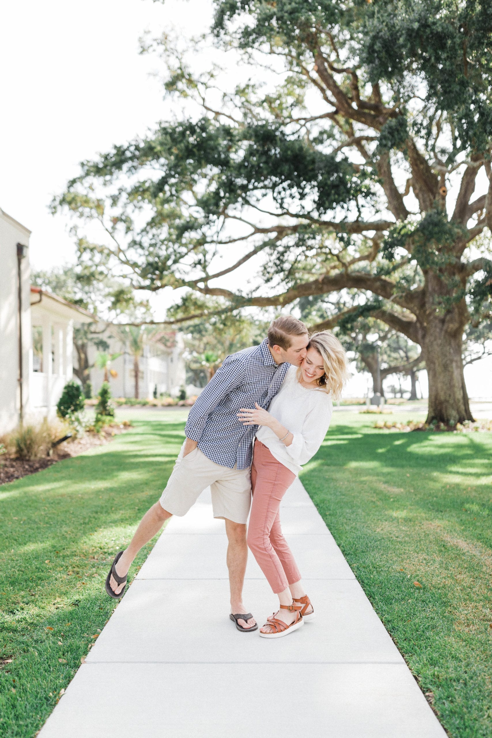 husband and wife stand on sidewalk, laughing