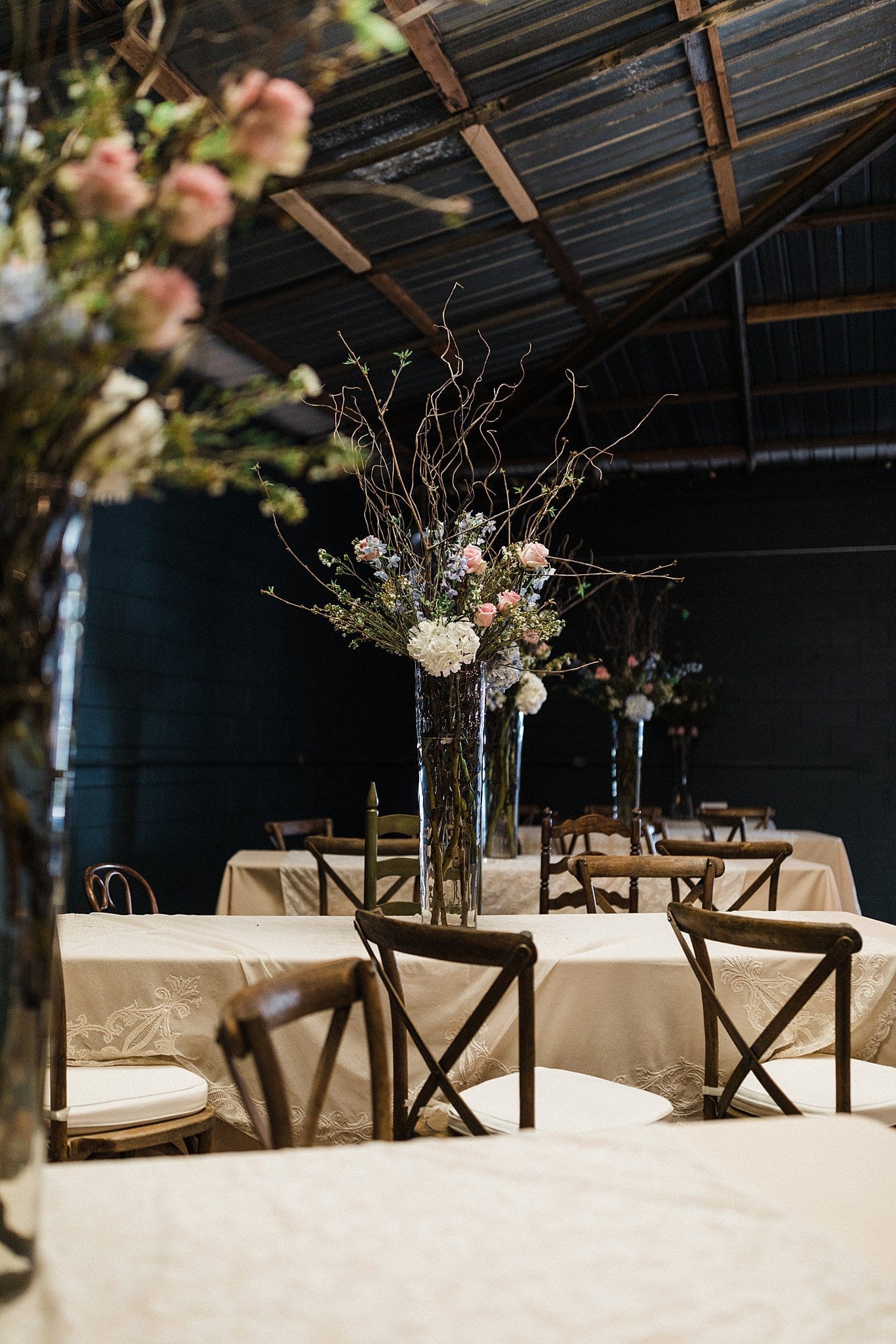 row of tables with floral centerpieces for ceremony